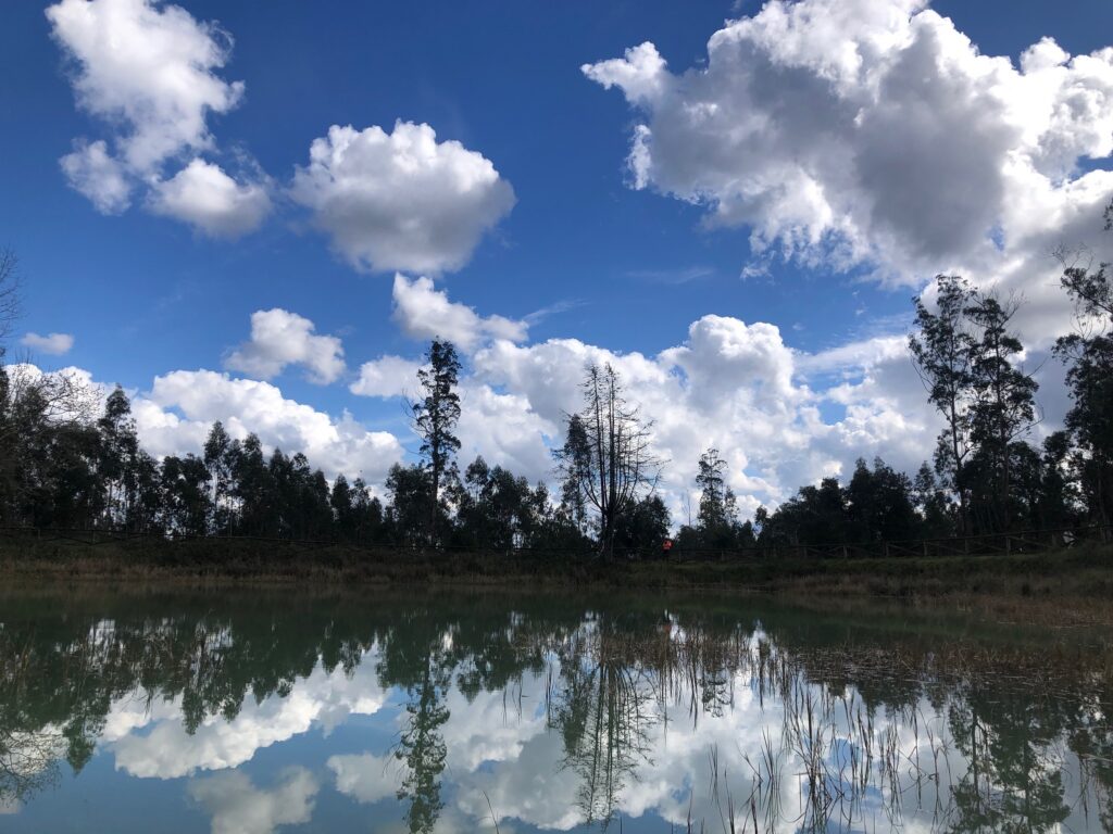 a beautiful turquoise lake with a blue sky and white clouds reflected in the lake
